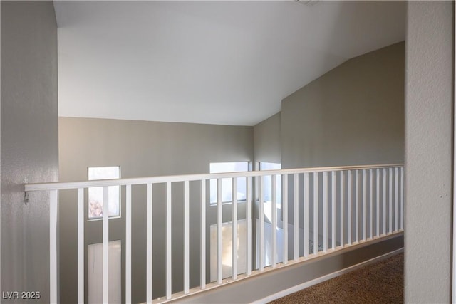 hallway with carpet floors, vaulted ceiling, and plenty of natural light