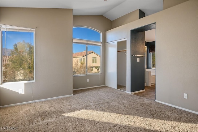 carpeted empty room featuring vaulted ceiling