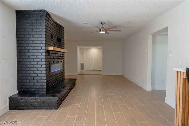 unfurnished living room with a brick fireplace, a textured ceiling, light hardwood / wood-style flooring, and ceiling fan