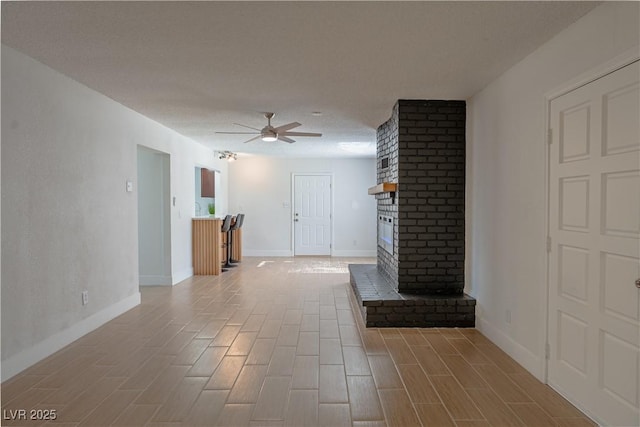 unfurnished living room with a textured ceiling, ceiling fan, and a fireplace