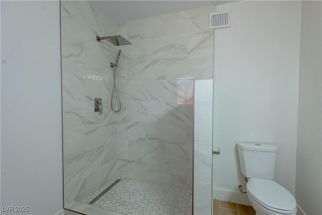 bathroom featuring toilet and a tile shower