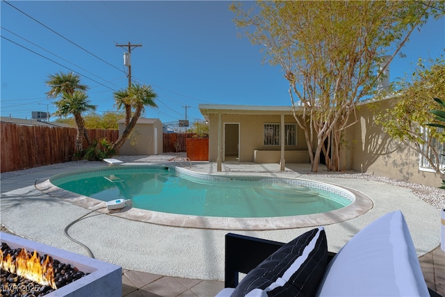 view of pool featuring an outdoor fire pit, a storage unit, and a patio