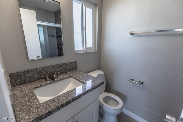 bathroom featuring toilet, a shower with door, plenty of natural light, and vanity