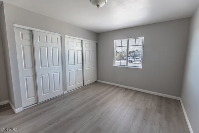 unfurnished bedroom featuring light hardwood / wood-style floors and two closets