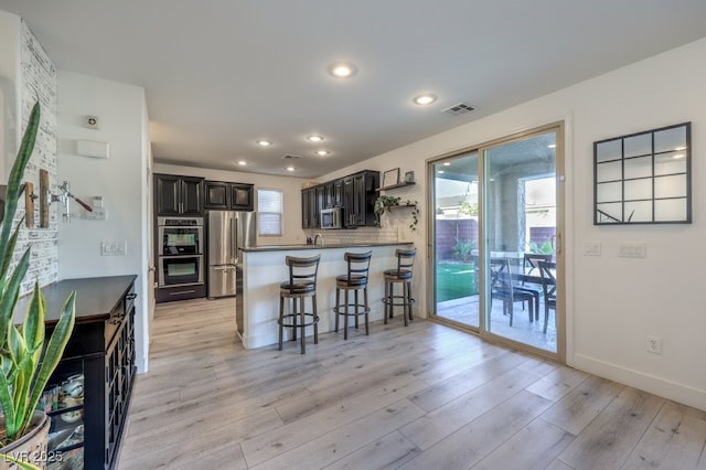 kitchen featuring a wealth of natural light, appliances with stainless steel finishes, kitchen peninsula, and light wood-type flooring