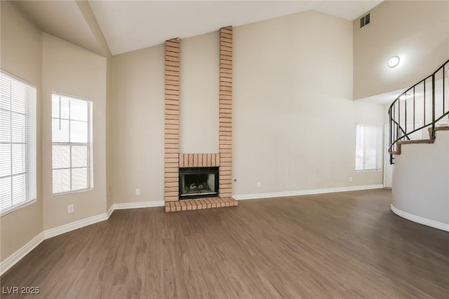 unfurnished living room featuring a brick fireplace, dark wood-type flooring, and high vaulted ceiling