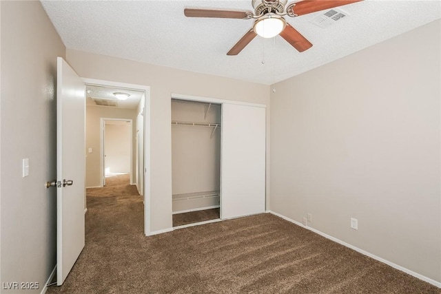 unfurnished bedroom with a textured ceiling, ceiling fan, a closet, and dark colored carpet