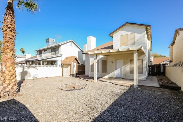 back of property with a patio area and a storage shed