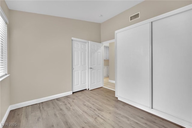 unfurnished bedroom with a closet and light hardwood / wood-style floors