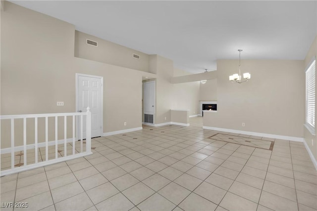 tiled spare room with lofted ceiling and an inviting chandelier