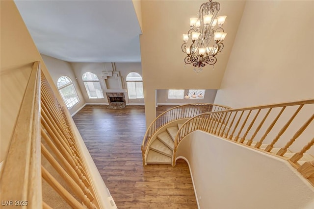 stairs with hardwood / wood-style floors, a high end fireplace, and an inviting chandelier