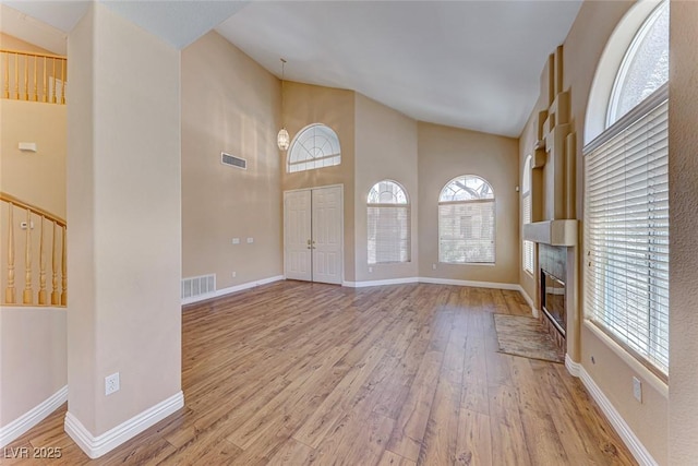 foyer entrance featuring high vaulted ceiling and light hardwood / wood-style flooring