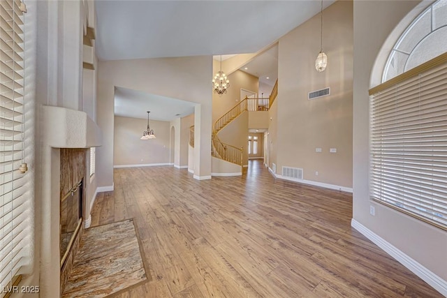 unfurnished living room with a brick fireplace, wood-type flooring, and high vaulted ceiling