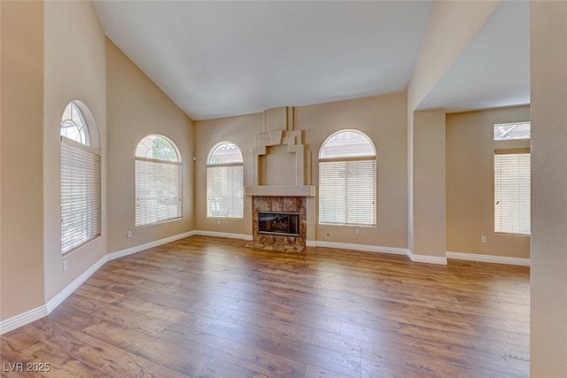 unfurnished living room featuring light wood-type flooring, a fireplace, and high vaulted ceiling