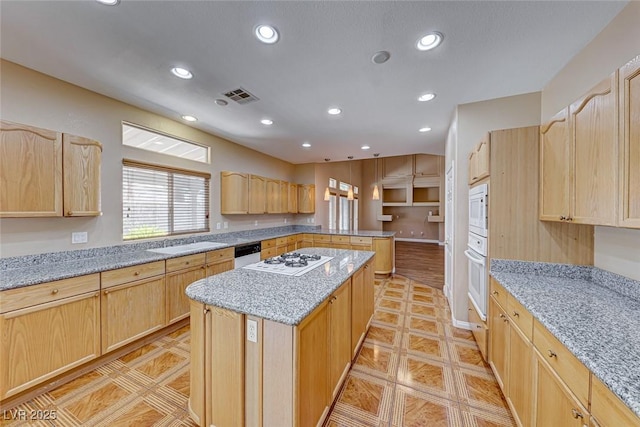 kitchen with a kitchen island, light tile patterned flooring, white appliances, light brown cabinetry, and light stone counters