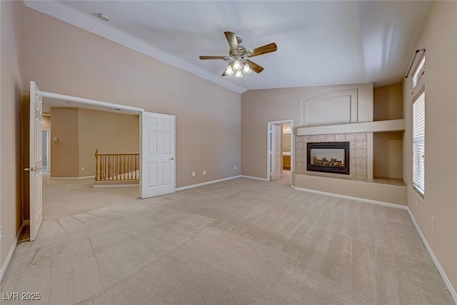 unfurnished living room with ceiling fan, light colored carpet, high vaulted ceiling, and a fireplace