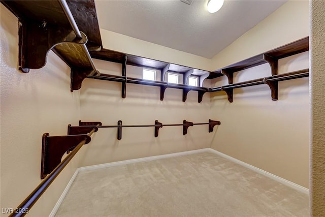 spacious closet with vaulted ceiling and light colored carpet