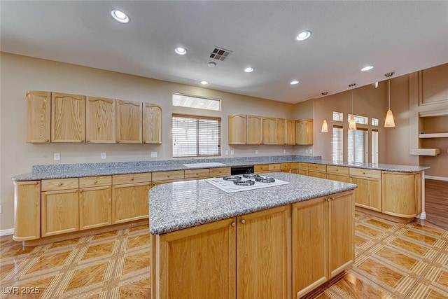 kitchen featuring kitchen peninsula, a kitchen island, light brown cabinetry, and white gas cooktop