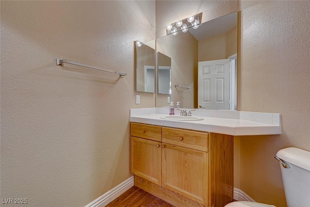 bathroom with toilet, vanity, and hardwood / wood-style flooring