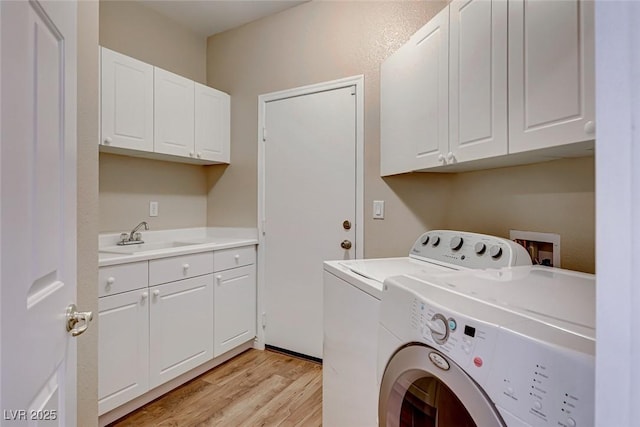 clothes washing area featuring light hardwood / wood-style flooring, independent washer and dryer, sink, and cabinets