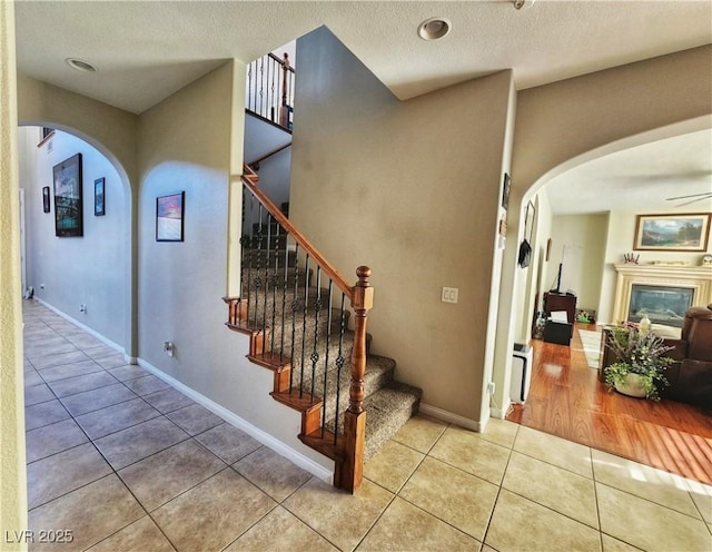 stairway featuring ceiling fan and tile patterned floors