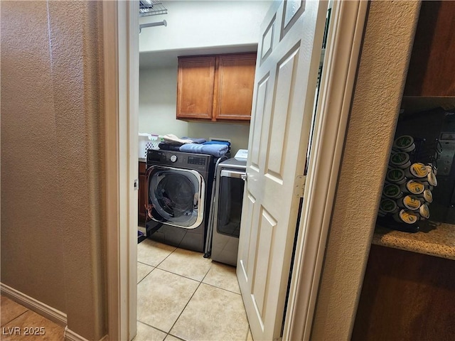 laundry area with cabinets, light tile patterned floors, and washer and clothes dryer