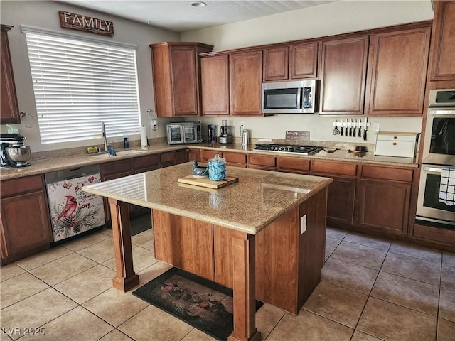 kitchen featuring light tile patterned flooring, sink, stainless steel appliances, and a kitchen island