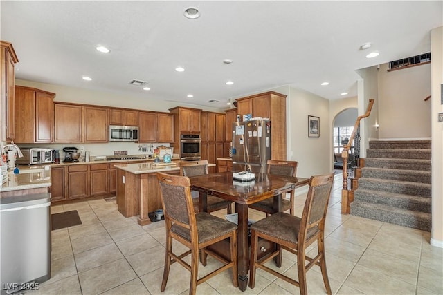 kitchen with light stone counters, a center island, light tile patterned floors, and stainless steel appliances