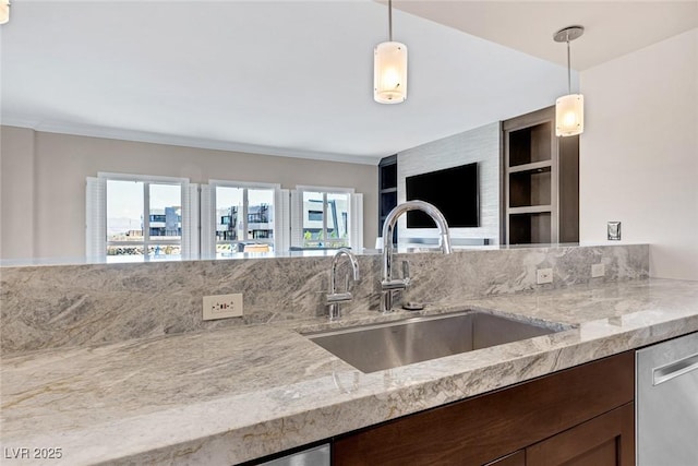 kitchen featuring built in shelves, decorative light fixtures, light stone counters, and sink