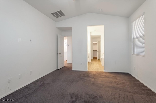 unfurnished bedroom with vaulted ceiling, ensuite bathroom, and carpet