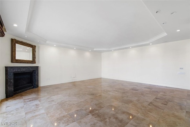 unfurnished living room with a high end fireplace and a raised ceiling