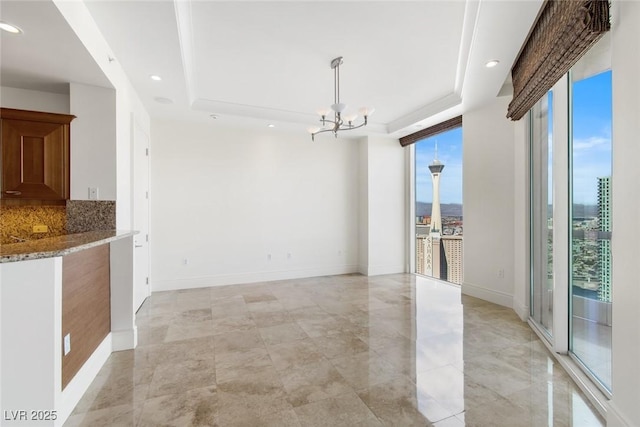 unfurnished dining area with a wall of windows, a raised ceiling, and a notable chandelier