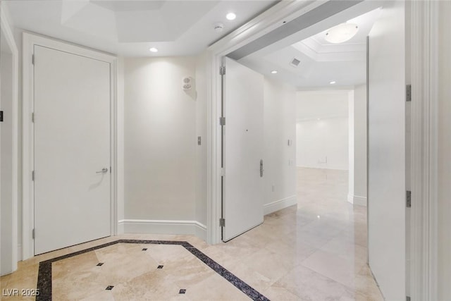 corridor featuring a tray ceiling and ornamental molding