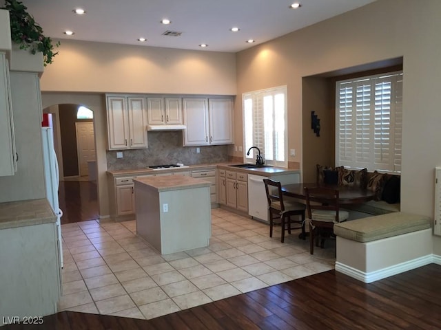 kitchen featuring backsplash, a center island, sink, white dishwasher, and gas stovetop