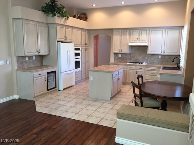 kitchen with sink, a center island, tasteful backsplash, and white appliances