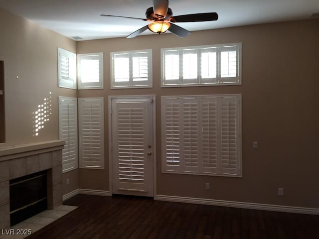 unfurnished living room with ceiling fan, hardwood / wood-style flooring, and a tile fireplace