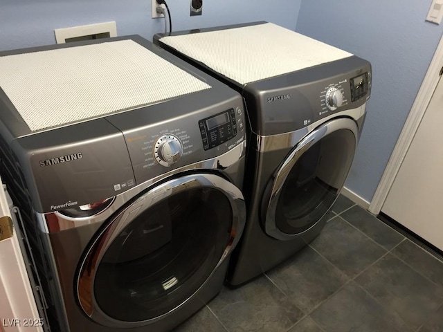 clothes washing area featuring dark tile patterned floors and washer and dryer