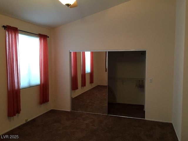 unfurnished bedroom featuring dark carpet and a closet