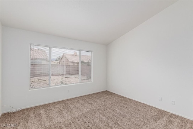 carpeted spare room with vaulted ceiling