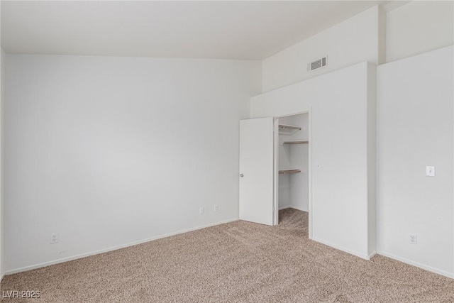 unfurnished bedroom featuring light carpet, a walk in closet, and a closet