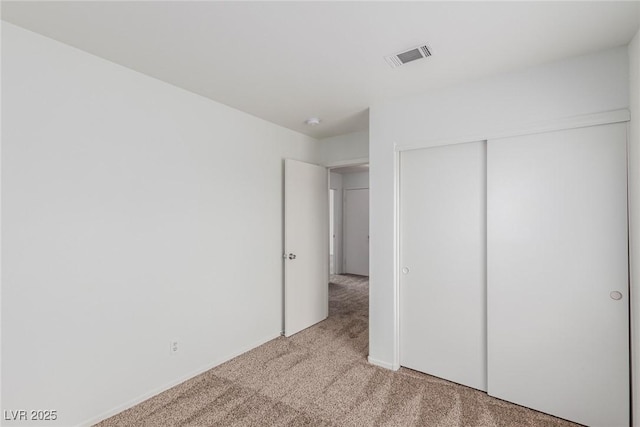 unfurnished bedroom featuring a closet and light colored carpet