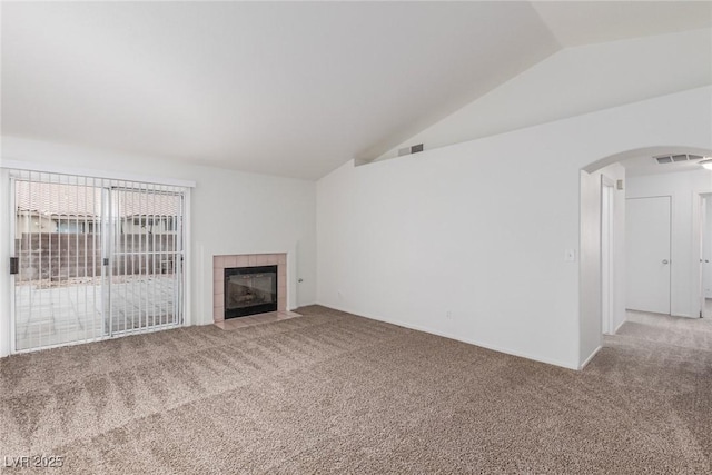 unfurnished living room featuring lofted ceiling, a tiled fireplace, and carpet