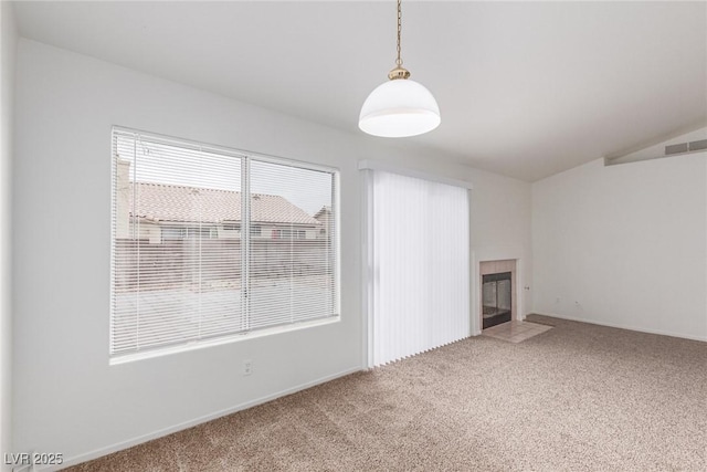 unfurnished living room with a tile fireplace, lofted ceiling, and carpet flooring