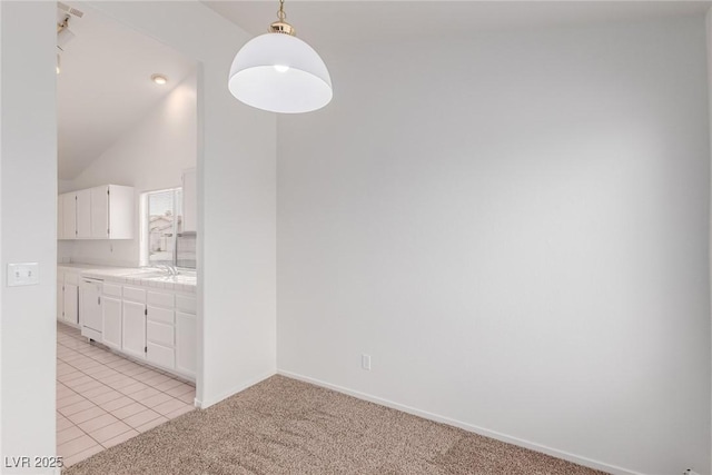 unfurnished dining area with sink, light carpet, and vaulted ceiling