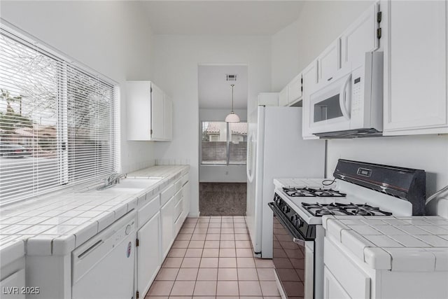 kitchen featuring white appliances, white cabinets, sink, tile countertops, and light tile patterned floors