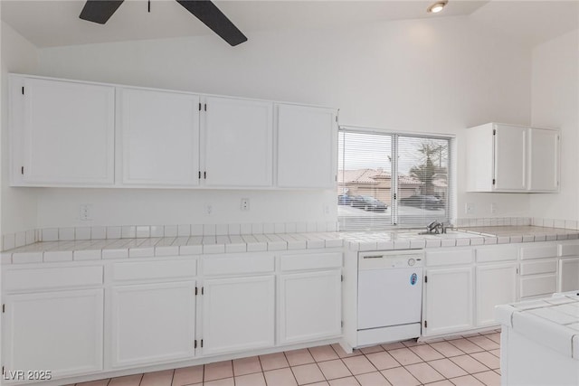 kitchen with light tile patterned floors, tile counters, white dishwasher, and white cabinetry