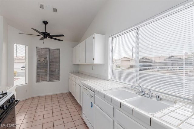 kitchen featuring ceiling fan, lofted ceiling, light tile patterned floors, tile counters, and white cabinets