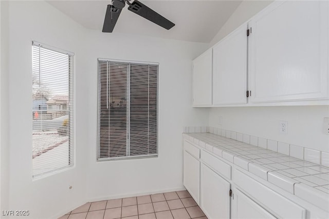 kitchen featuring ceiling fan, white cabinetry, tile countertops, and light tile patterned flooring