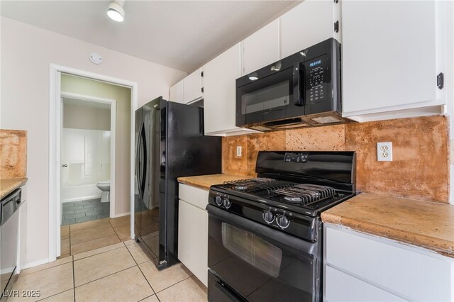 kitchen featuring black appliances, light tile patterned floors, backsplash, and white cabinetry