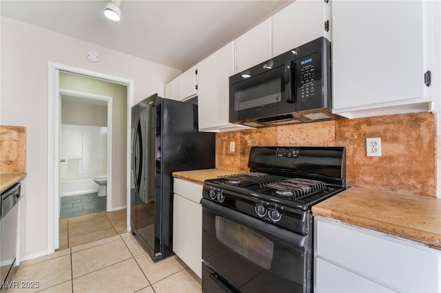 kitchen featuring white cabinetry, light tile patterned floors, decorative backsplash, and black appliances